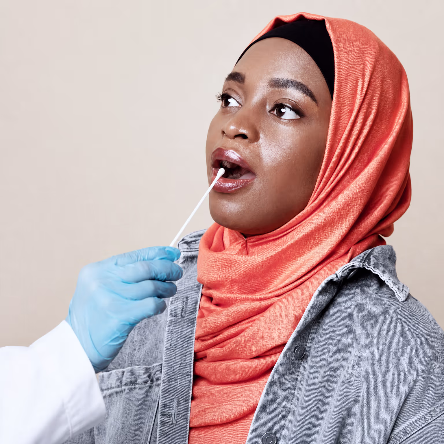 Woman in a hijab receiving a cheek swab for genetic testing
