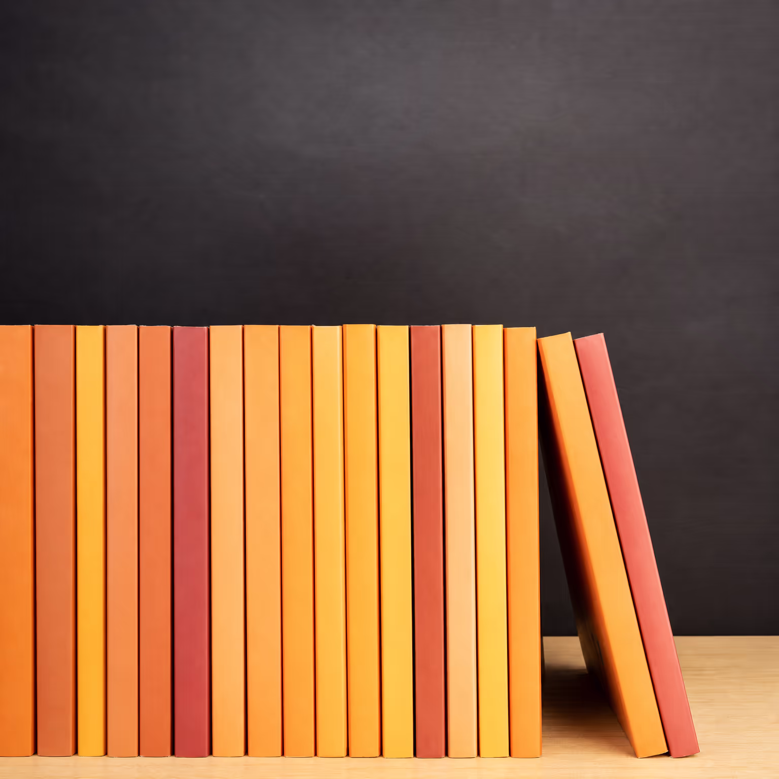 Row of orange books lined up neatly against a dark wall