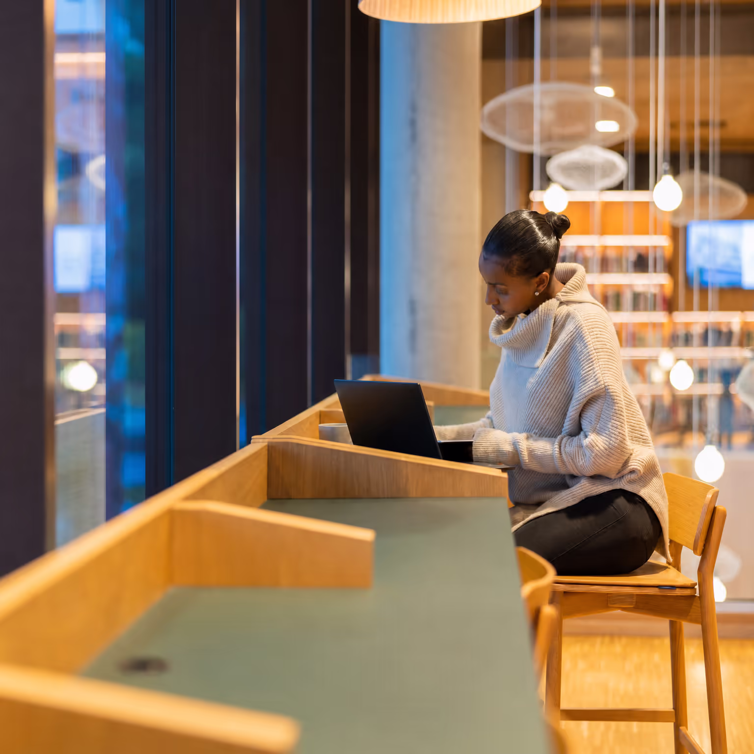 Young woman studying on a laptop in a campus library
